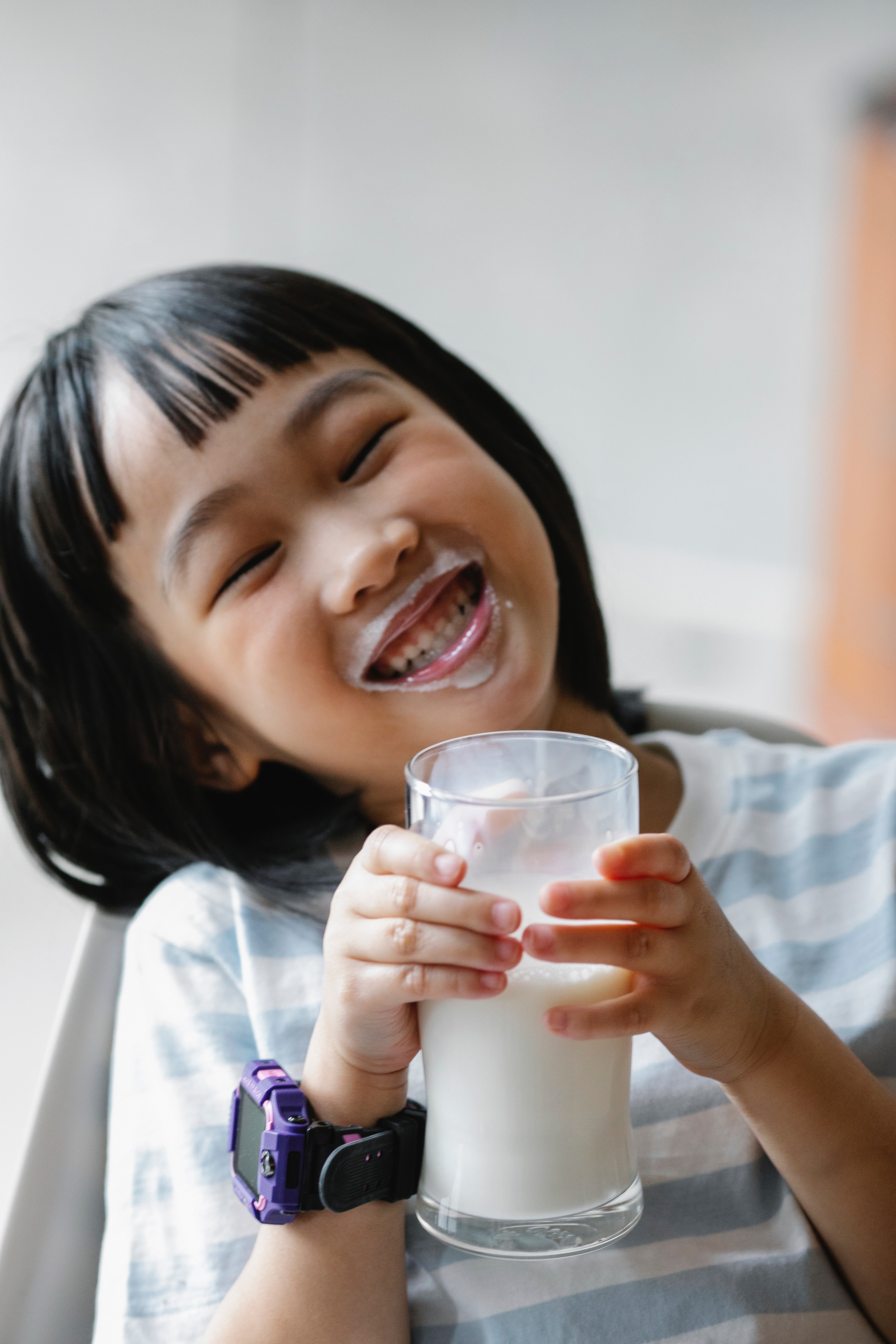 kid with a big smile holding a glass of milk